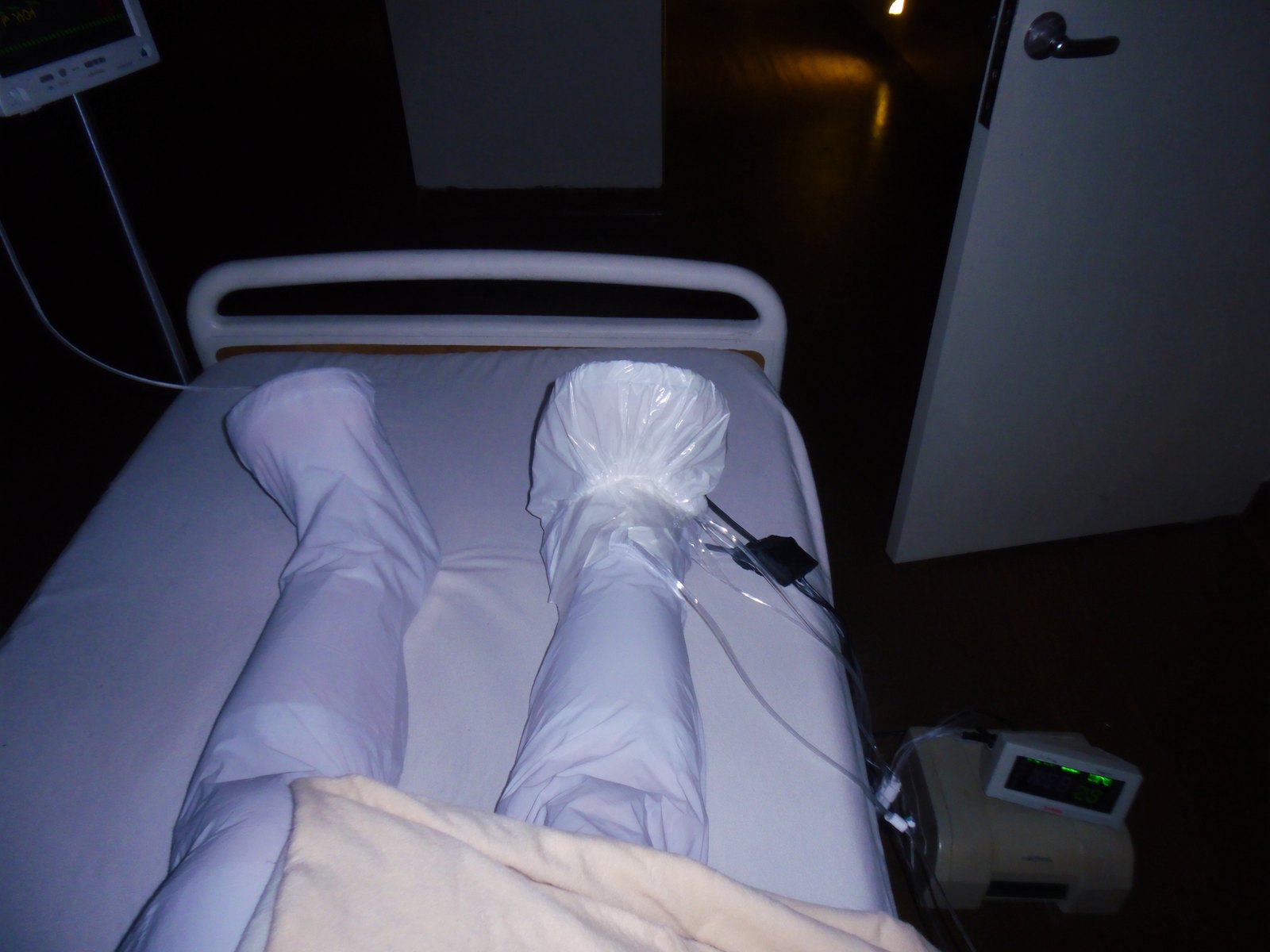Hospital bed at night with compression sleeves on a patient's legs