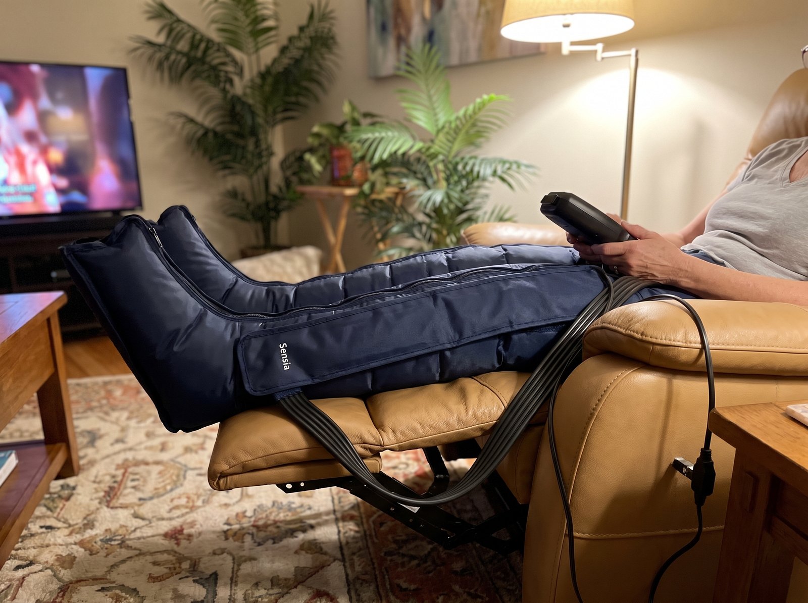 Sensia Wave boots on a woman's legs in a recliner, controller in hand